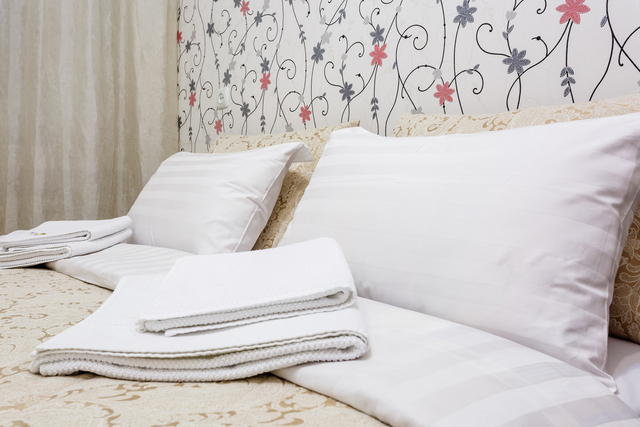 Double bed with pillows in interior of the modern bedroom in loft flat in light color style of expensive apartments